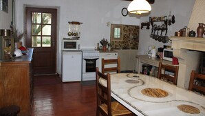A kitchen with a wooden table, chairs, a stove, and a microwave. - Village house Entrechaux (Entrechaux)
