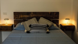 A bed with a wooden headboard, two bedside tables, and two lamps.