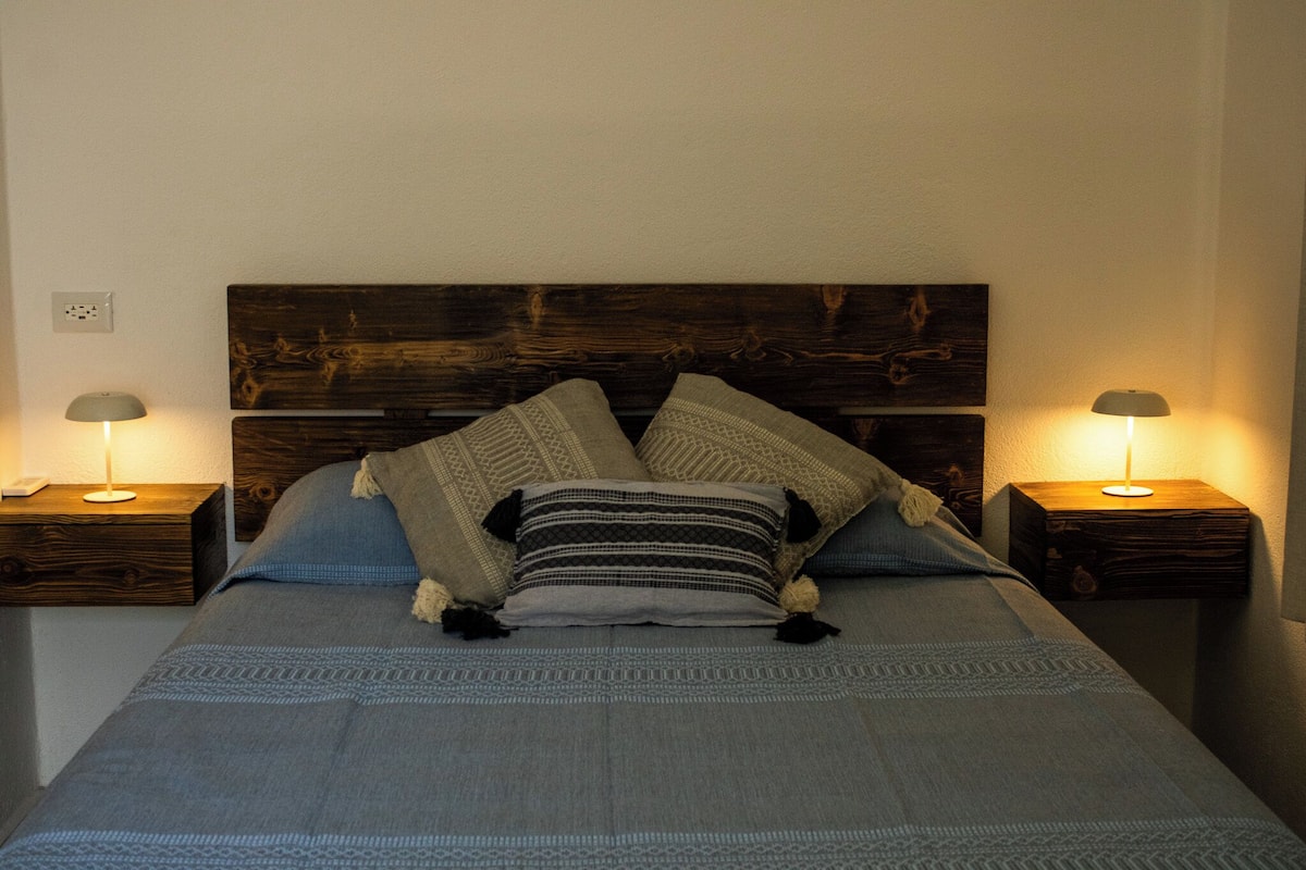 A bed with a wooden headboard, two bedside tables, and two lamps.