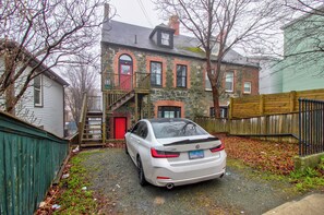 A white car parked in a driveway with a stone building in the background. - CIRCA 1800 TWO-STORY EXECUTIVE RENTAL SUITE (St. John's)