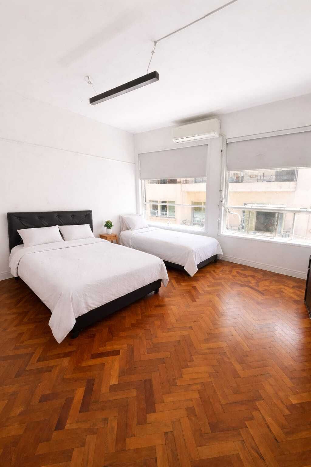 Een moderne slaapkamer met twee bedden, houten vloeren en grote ramen.