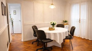 A dining room with a round table, four chairs, a vase of flowers, and a hanging light fixture. - Private rooms in the city center (Buenos Aires)