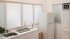 A compact kitchen with white cabinets, a sink, a microwave, and a refrigerator. - Private rooms in the city center (Buenos Aires)