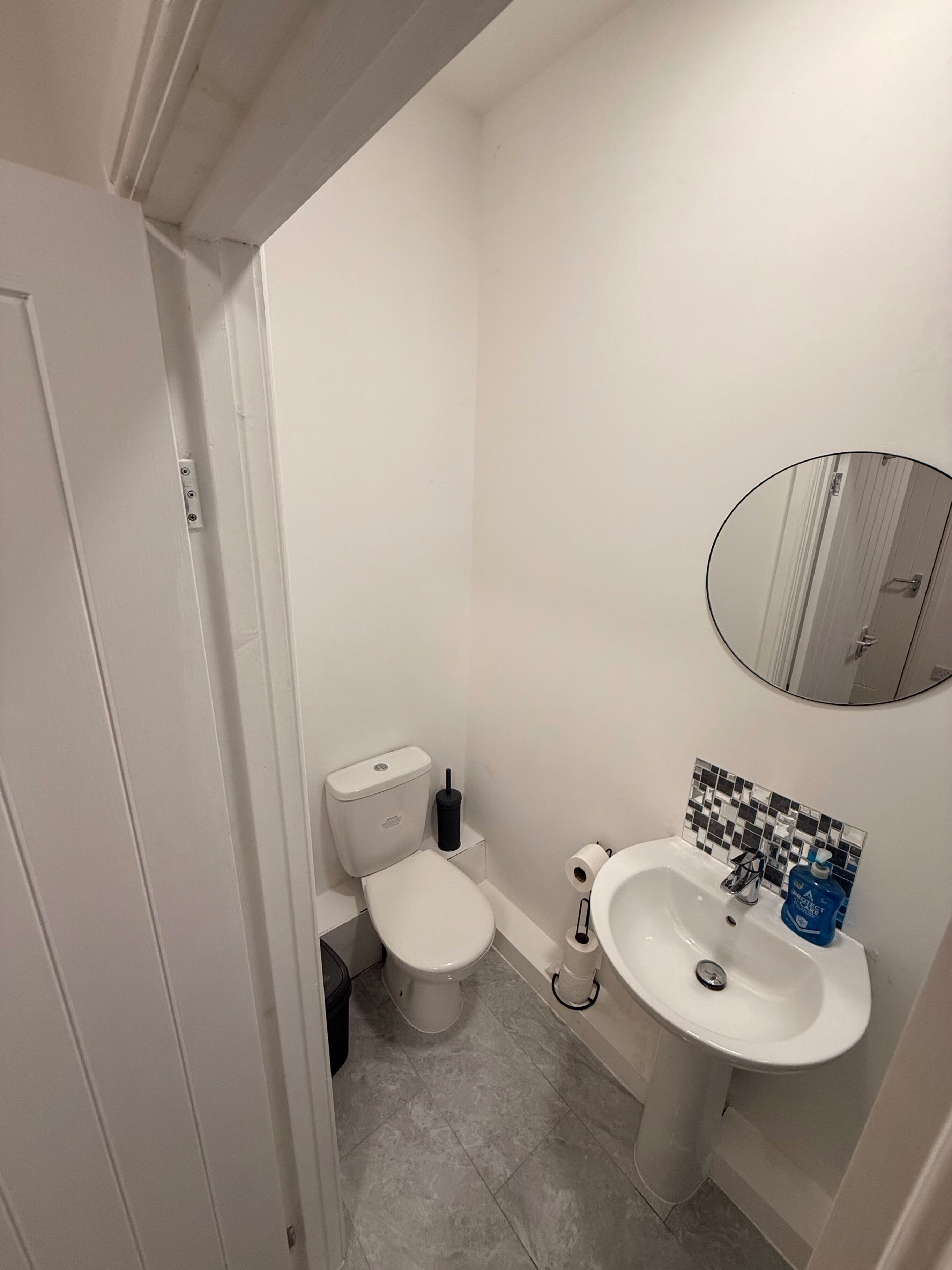 A small, clean bathroom with a toilet, sink, and mirror.