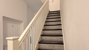 A staircase with white railings and dark carpeted steps leading to a door marked with the number 1. - Stylish Dream Home With 4 En-suite Bedrooms (Liverpool)