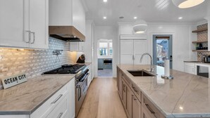 Una cocina moderna con armarios blancos, una isla central y vistas al salón.