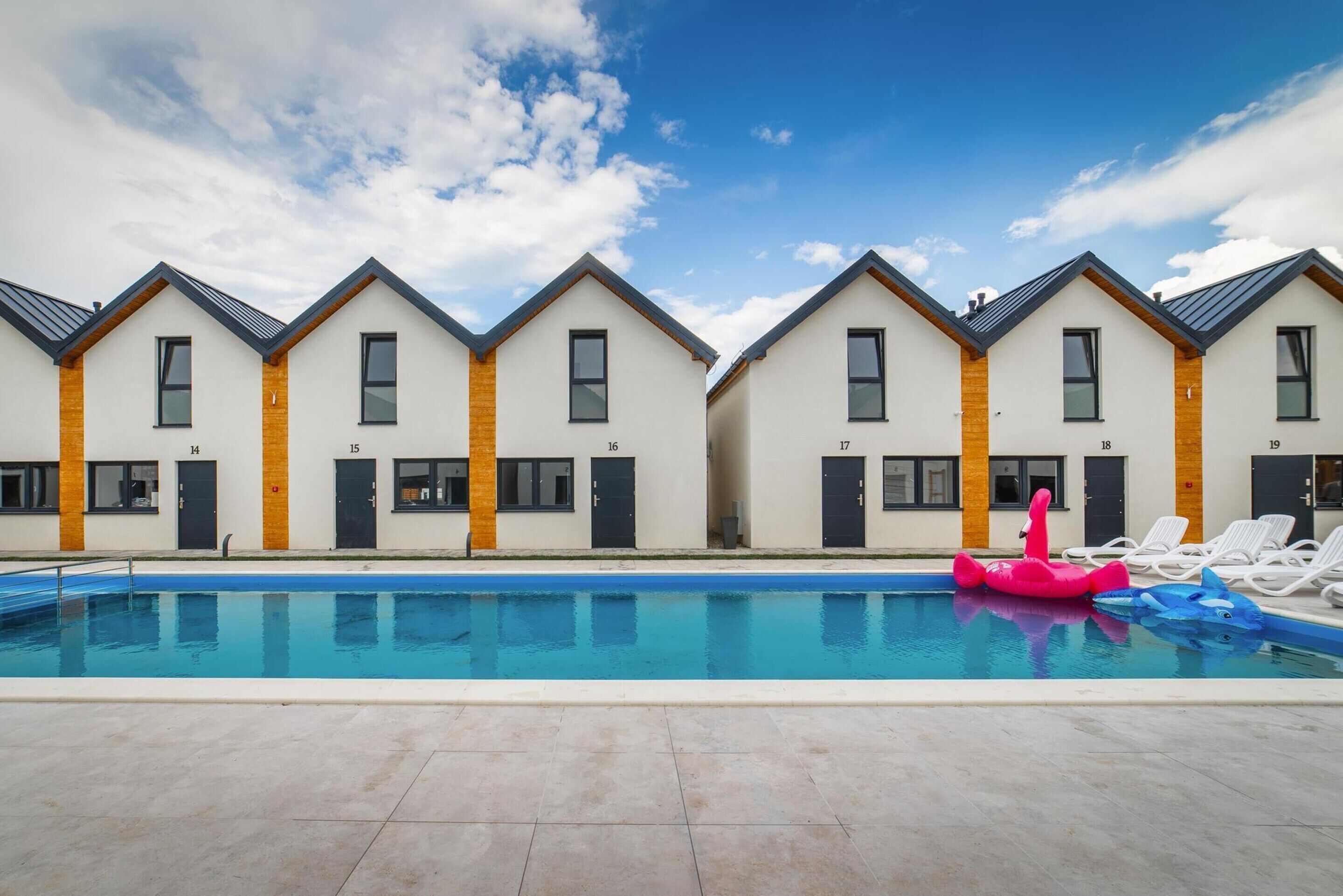 En rad moderna hotellrum med nummer, en swimmingpool och uppblåsbara leksaker.