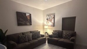 Un salon avec deux canapés, une lampe sur pied et deux tableaux accrochés au mur.
