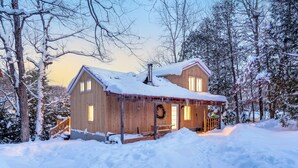 A wooden cabin with a chimney, surrounded by snow-covered trees. - Getaway 1 hour from Montreal - perfect for relaxing (Saint-Calixte)