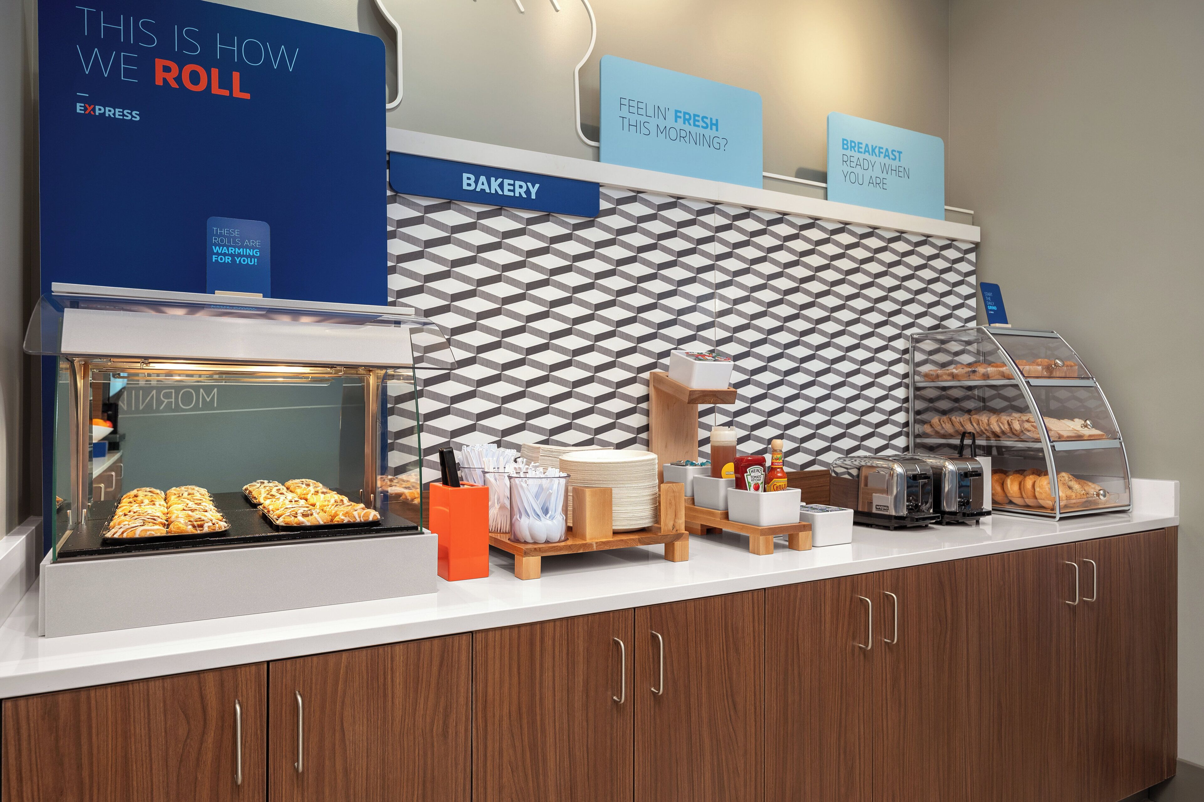 Mostrador de panadería con pasteles, una máquina de café y un letrero que dice 'FEELIN' FRESH THIS MORNING?'