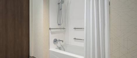 A modern bathroom with a bathtub, shower, and wooden door.