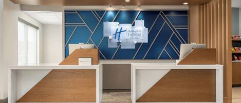 A reception desk with a blue geometric wall design and a Holiday Inn Express sign.