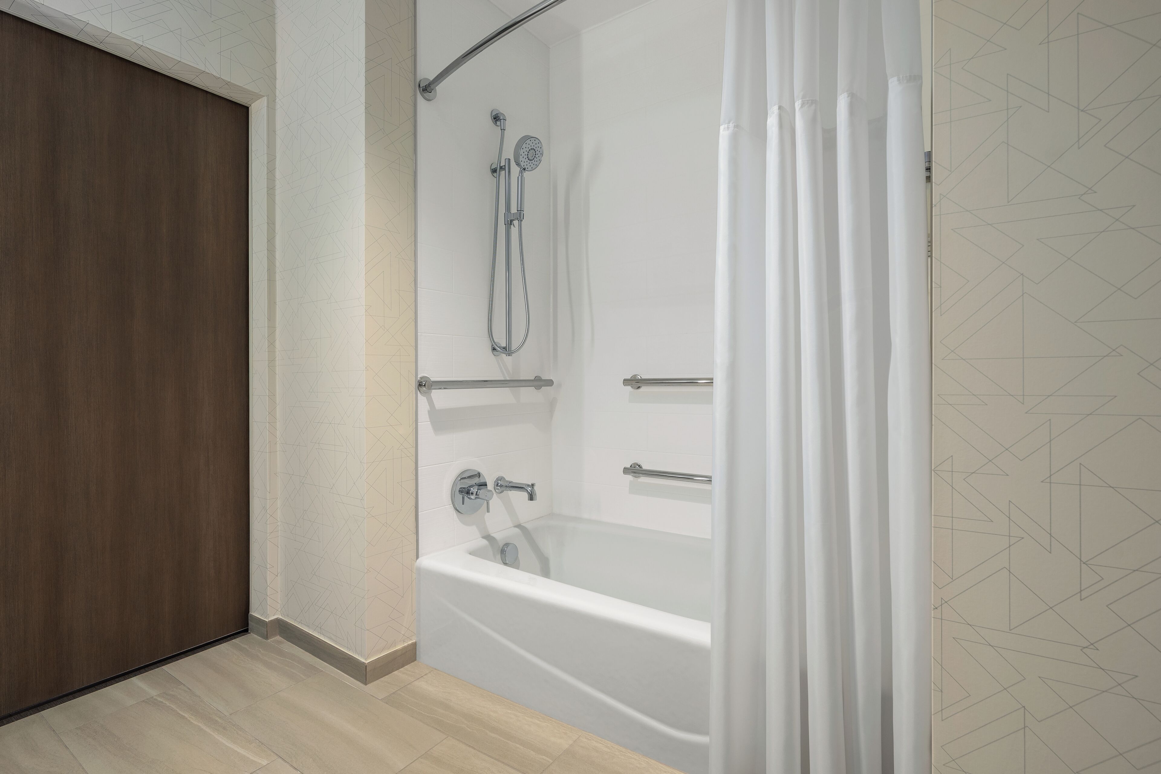 Un baño moderno con bañera, ducha y puerta de madera.