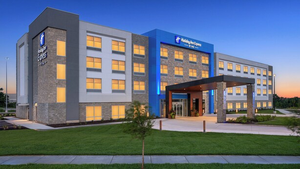 Un hotel Holiday Inn Express con un diseño moderno, que presenta una entrada destacada y un césped bien cuidado.