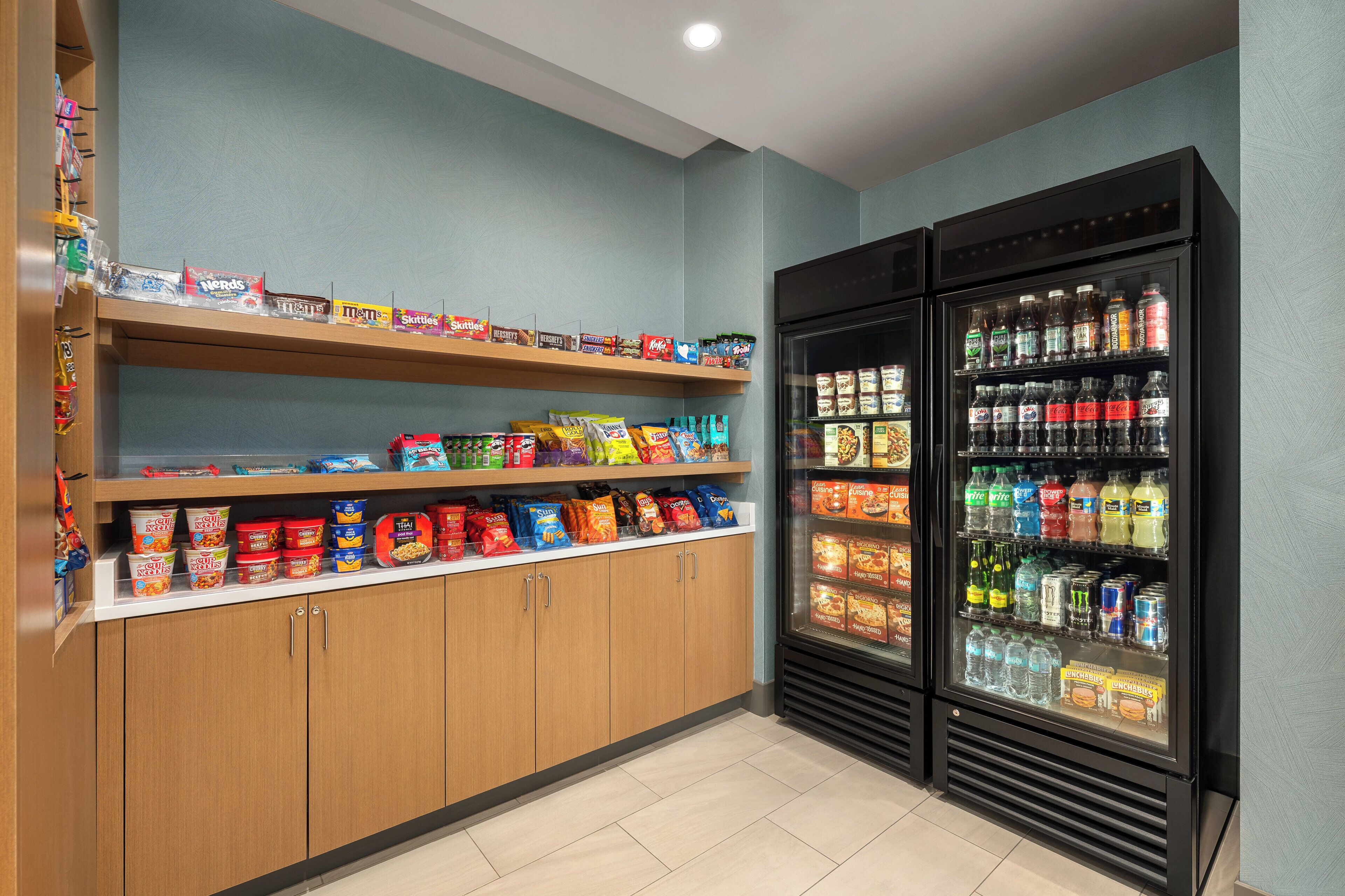 Un'area espositiva per snack e bevande, con scaffali e un frigorifero.