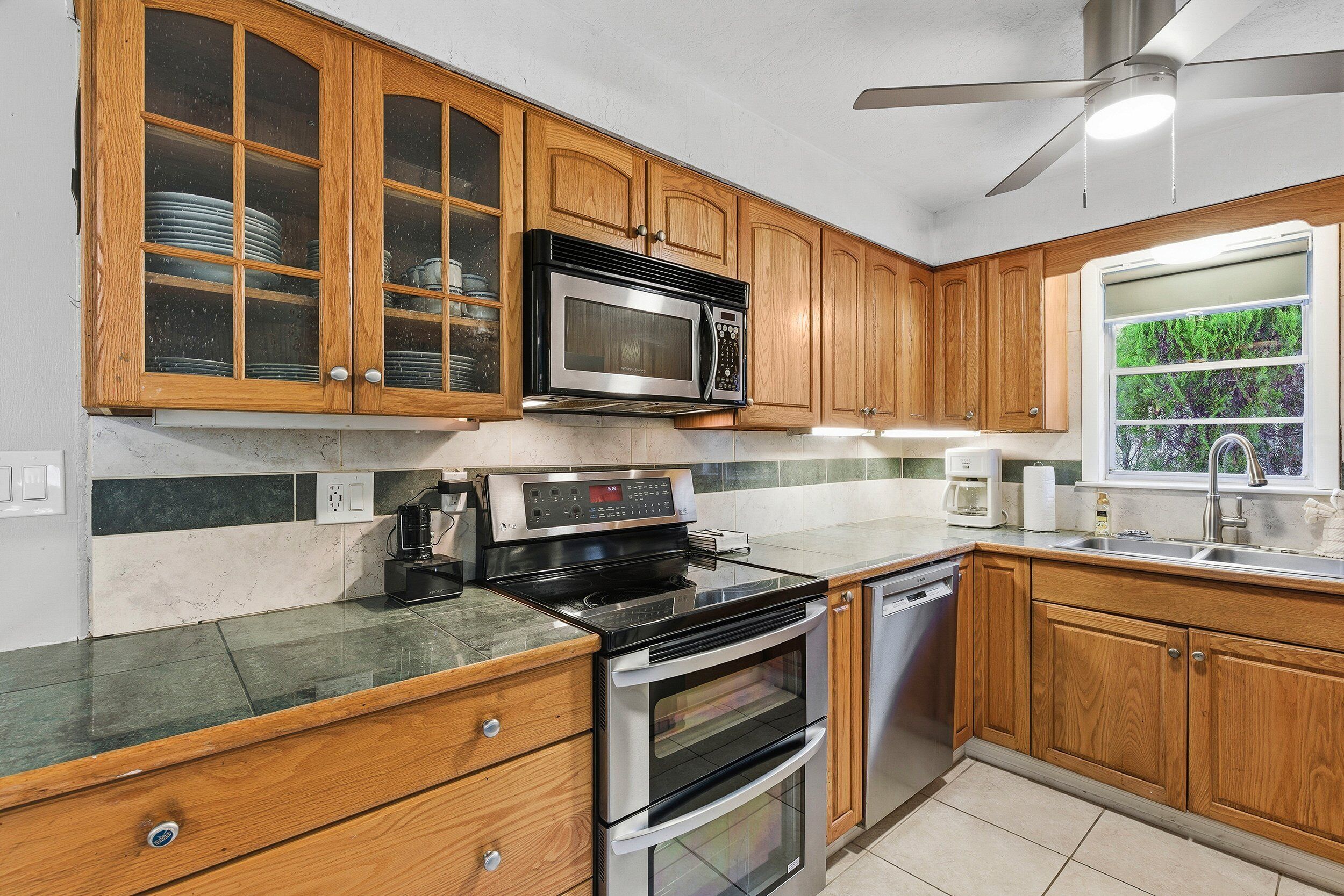 A kitchen with wooden cabinets, a microwave, stove, oven, and dishwasher.