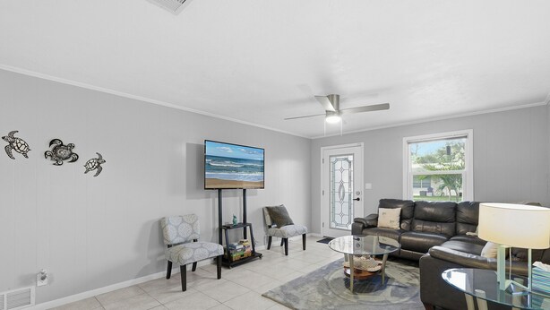 Ein Wohnzimmer mit Flachbildfernseher, Deckenventilator, Sofa und Couchtisch.