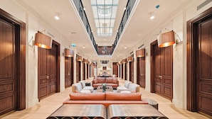 A hotel lobby with a central seating area, wooden doors, and a skylight.