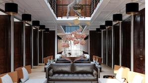 A spacious lobby with a central seating area, a high ceiling with a skylight, and a decorative sculpture.
