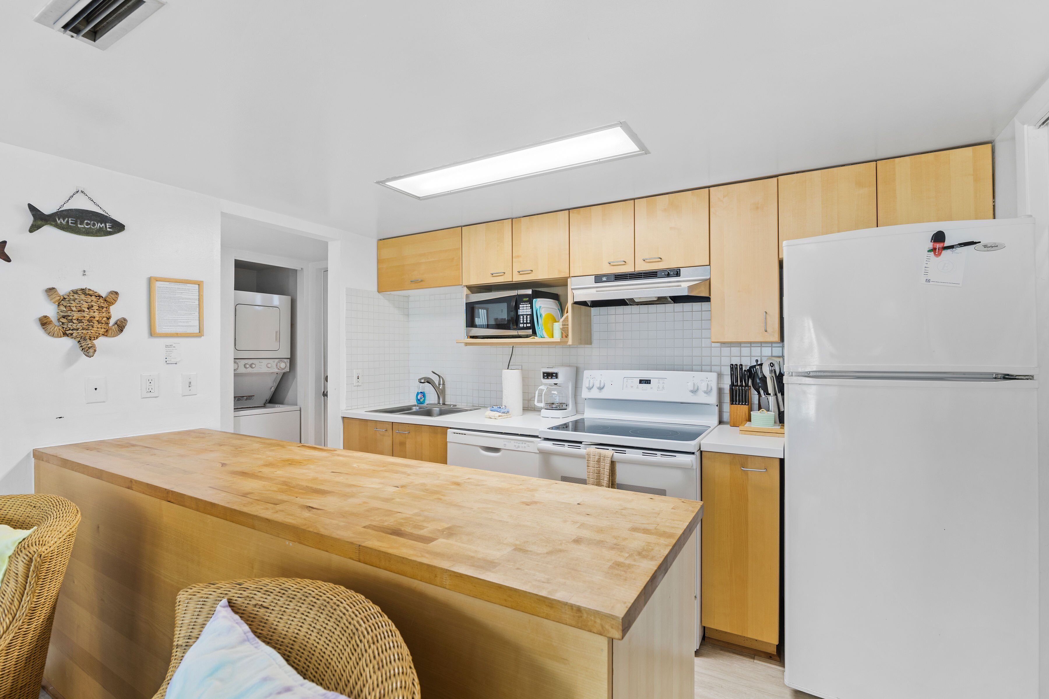 A modern kitchen with wooden cabinets, white appliances, and a wooden island.