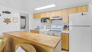 Una cucina moderna con mobili in legno, elettrodomestici bianchi e un'isola anch'essa in legno.
