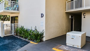 Un edificio con un’area di carico segnalata, un armadietto tecnico bianco e un balcone con ringhiera.