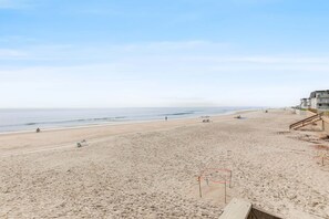 A beach with a wooden walkway leading to a building with multiple floors. - Seaward D-102 (New Smyrna Beach)
