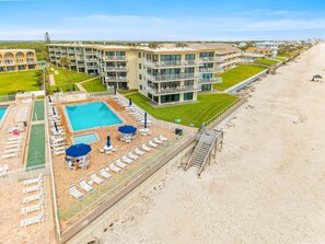 A hotel with a pool, sun loungers, and a beach view. - Seaward D-102 (New Smyrna Beach)