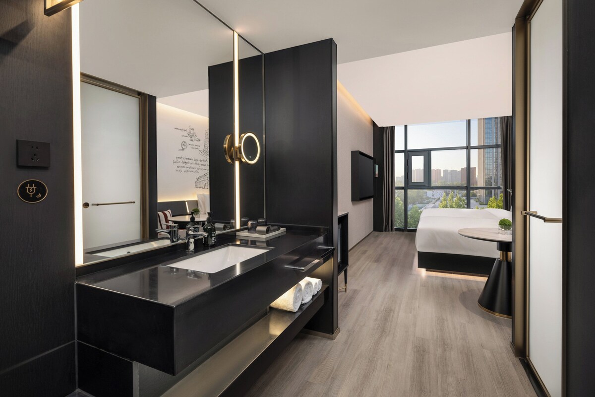A modern hotel bathroom with a large mirror, dual sinks, and a vanity.