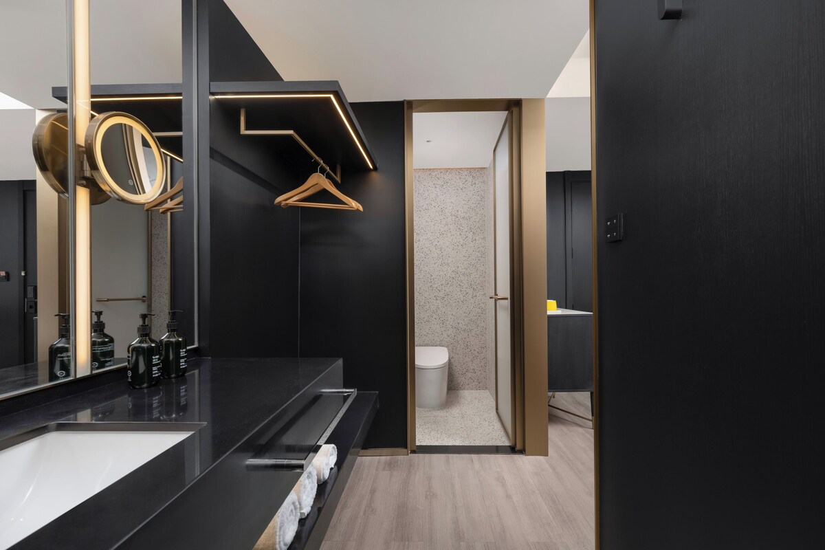 A modern bathroom with a black vanity, a mirror, and a towel rack.