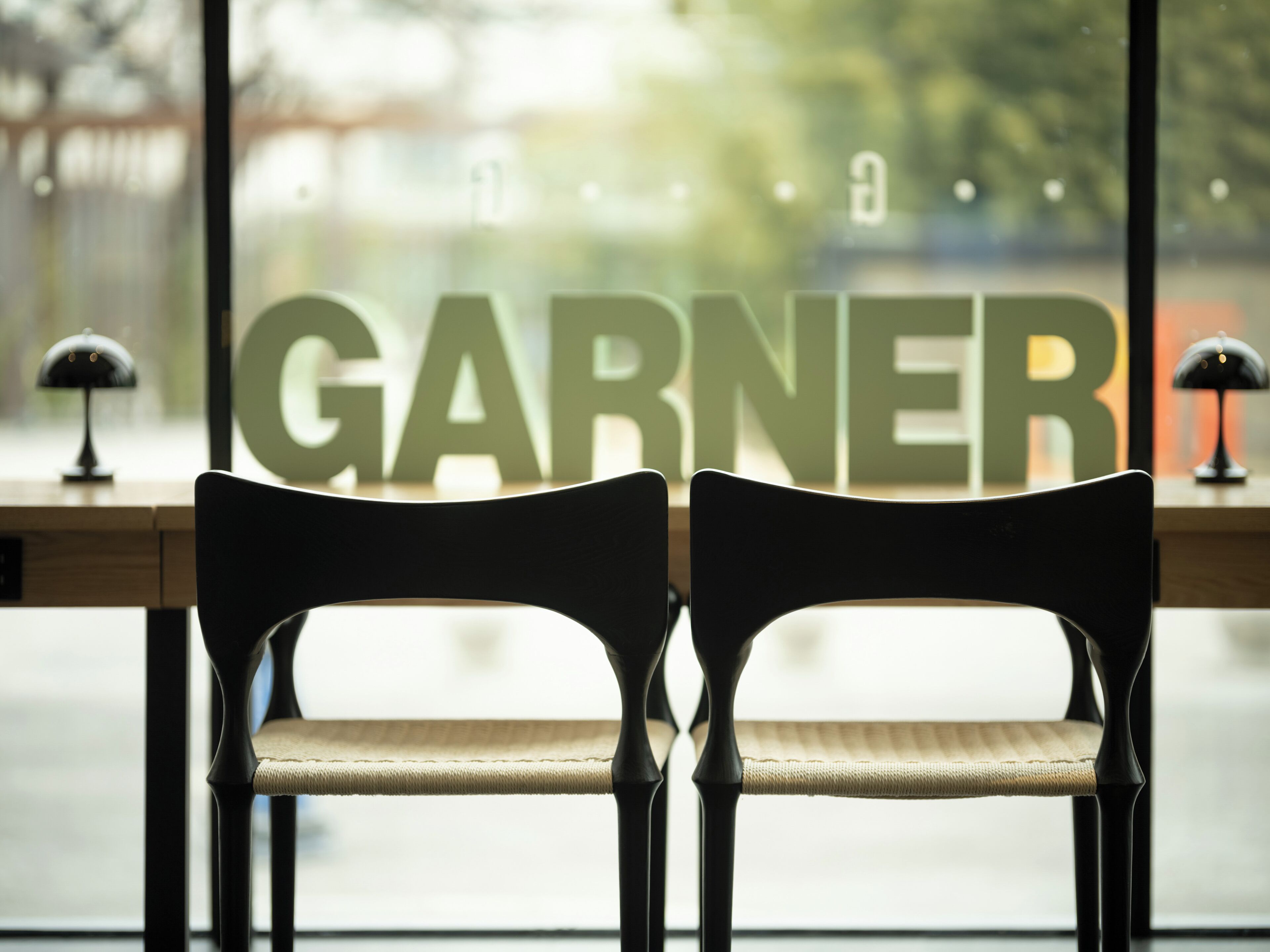 Twee stoelen gericht naar een raam, waarop 'GARNER' op de vensterbank staat.