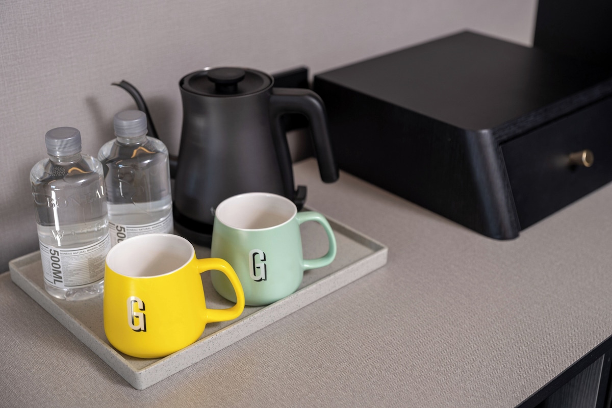 A tray with two mugs and two water bottles on a countertop.