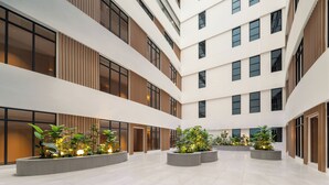 Un atrium à plusieurs niveaux, doté d’un jardin central, de grandes fenêtres et d’une architecture moderne.