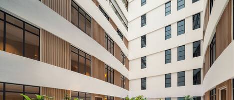 A multi-level atrium with a central garden area, large windows, and a modern architectural design.