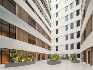 A multi-level atrium with a central garden area, large windows, and a modern architectural design. - Holiday Inn Express Xinxiang Pingyuan New Area By Ihg (Xinxiang)