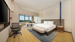 Une chambre d’hôtel moderne dotée d’un grand lit, d’un bureau, d’une chaise, d’une télévision et offrant une vue sur l’extérieur.