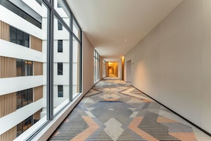A corridor with patterned flooring, large windows, and a modern building facade. - Holiday Inn Express Xinxiang Pingyuan New Area By Ihg (Xinxiang)