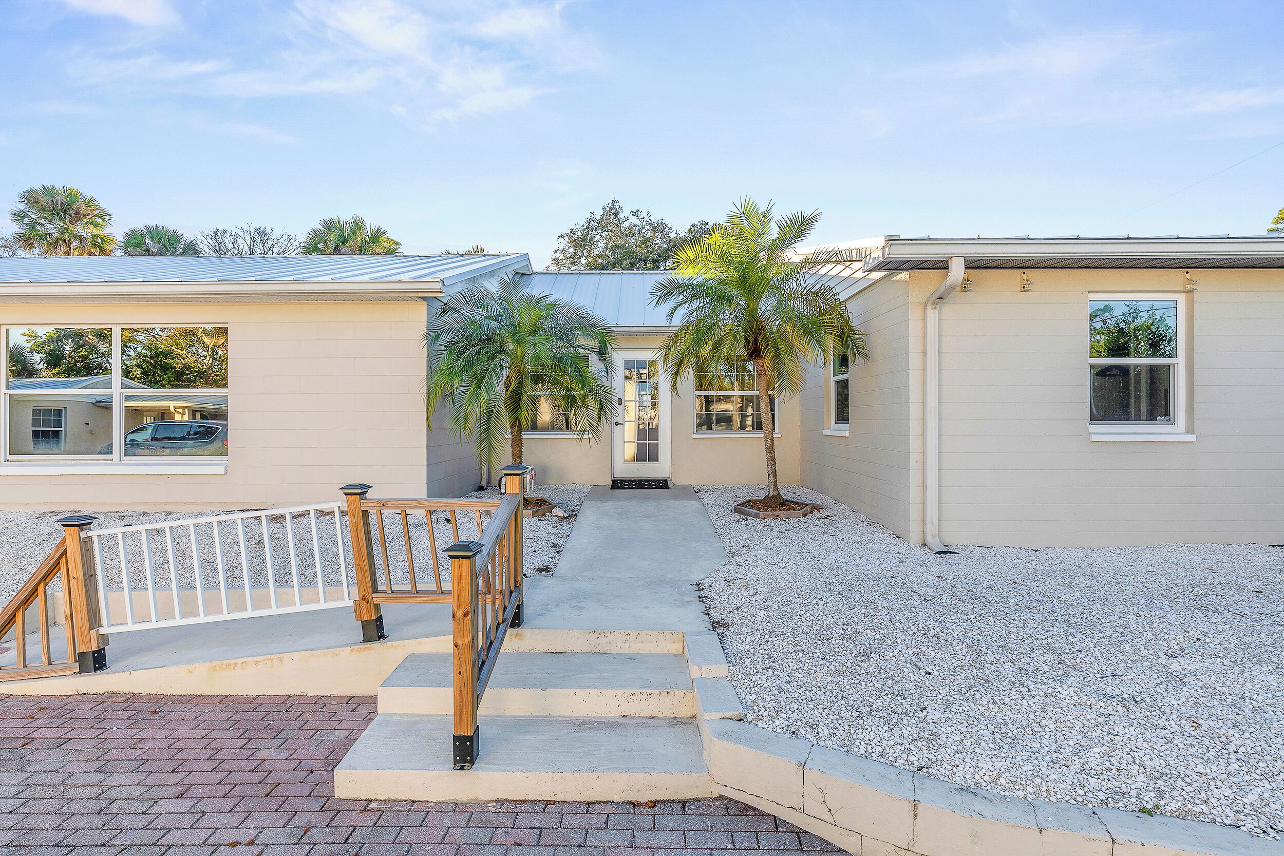 A two-story house with a front porch, a gravel driveway, and a wooden fence.
