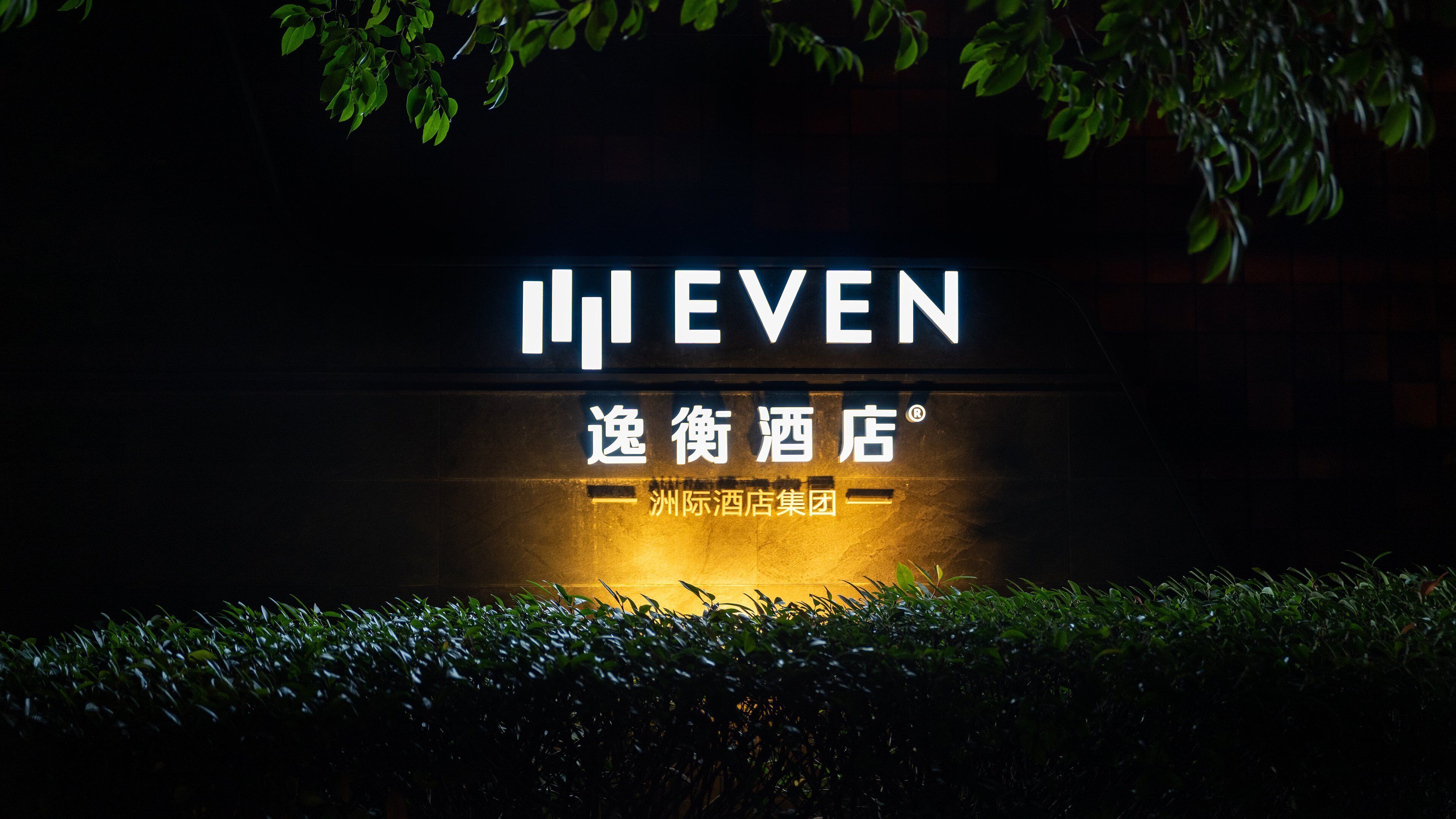 A hotel sign with illuminated text, a name in both English and Chinese, and a logo indicating a hotel group affiliation.