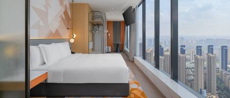 A modern hotel room with a large bed, a city view, and a balcony.