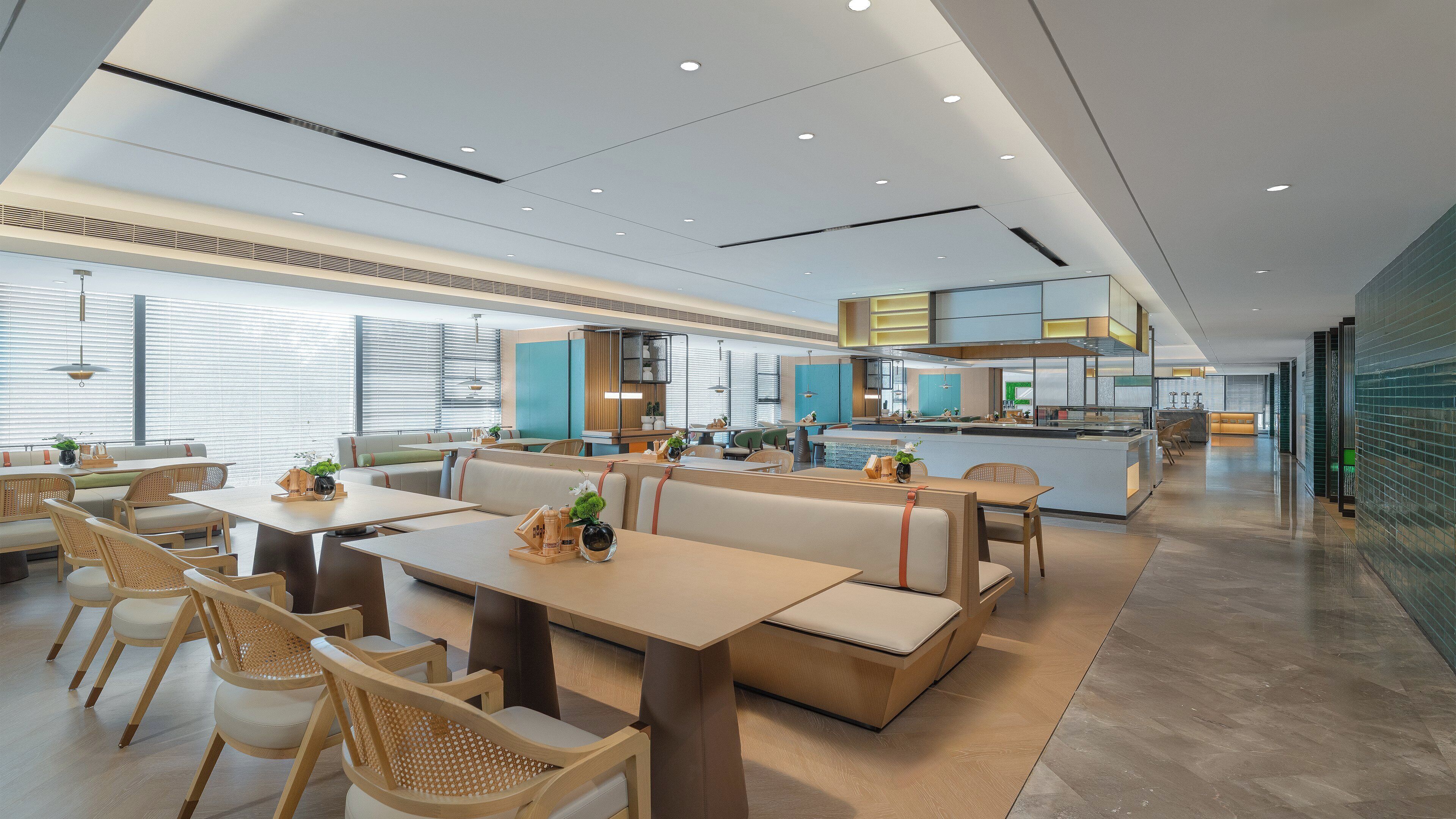 A modern restaurant with high ceilings, recessed lighting, and a mix of seating options including booths and tables.