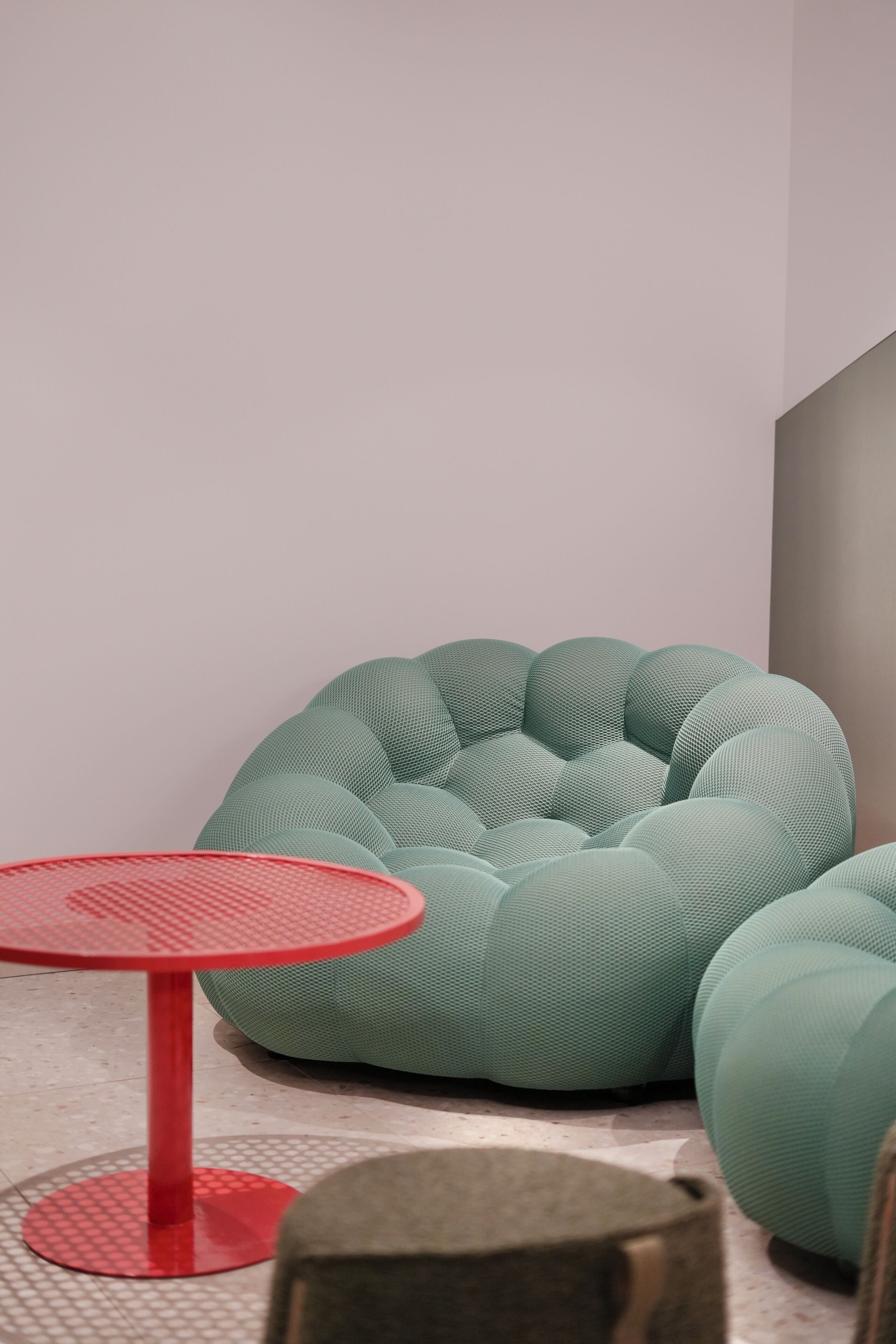 Un interior moderno con una zona de estar verde y con textura, y una mesa roja.
