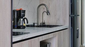 Una cocina moderna con microondas integrado, cafetera y refrigerador de acero inoxidable.