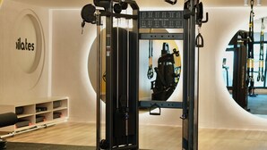 Un gimnasio con una estructura para sentadillas, un banco de pesas y un espejo montado en la pared.