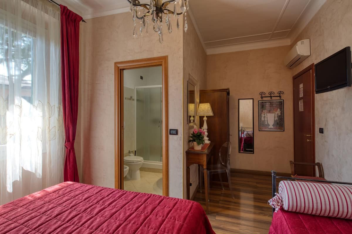 A hotel room with two beds, a bathroom, a hallway, and a dining area.
