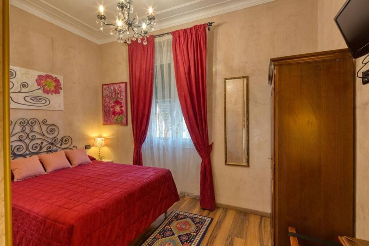 A bedroom with a bed, a chandelier, a wooden door, and artwork on the walls.