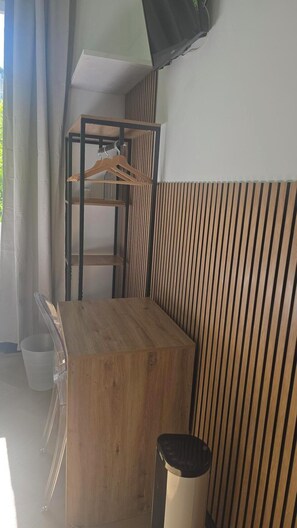 Une pièce avec un lit superposé en bois, une petite table, une poubelle et un luminaire suspendu.