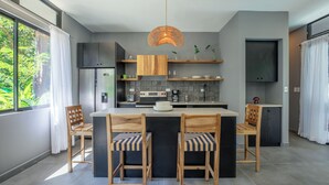 Una cucina moderna con isola centrale, sedie in legno e una lampada a sospensione.