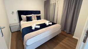 Un letto ben rifatto con una testiera, un comodino e una tenda.