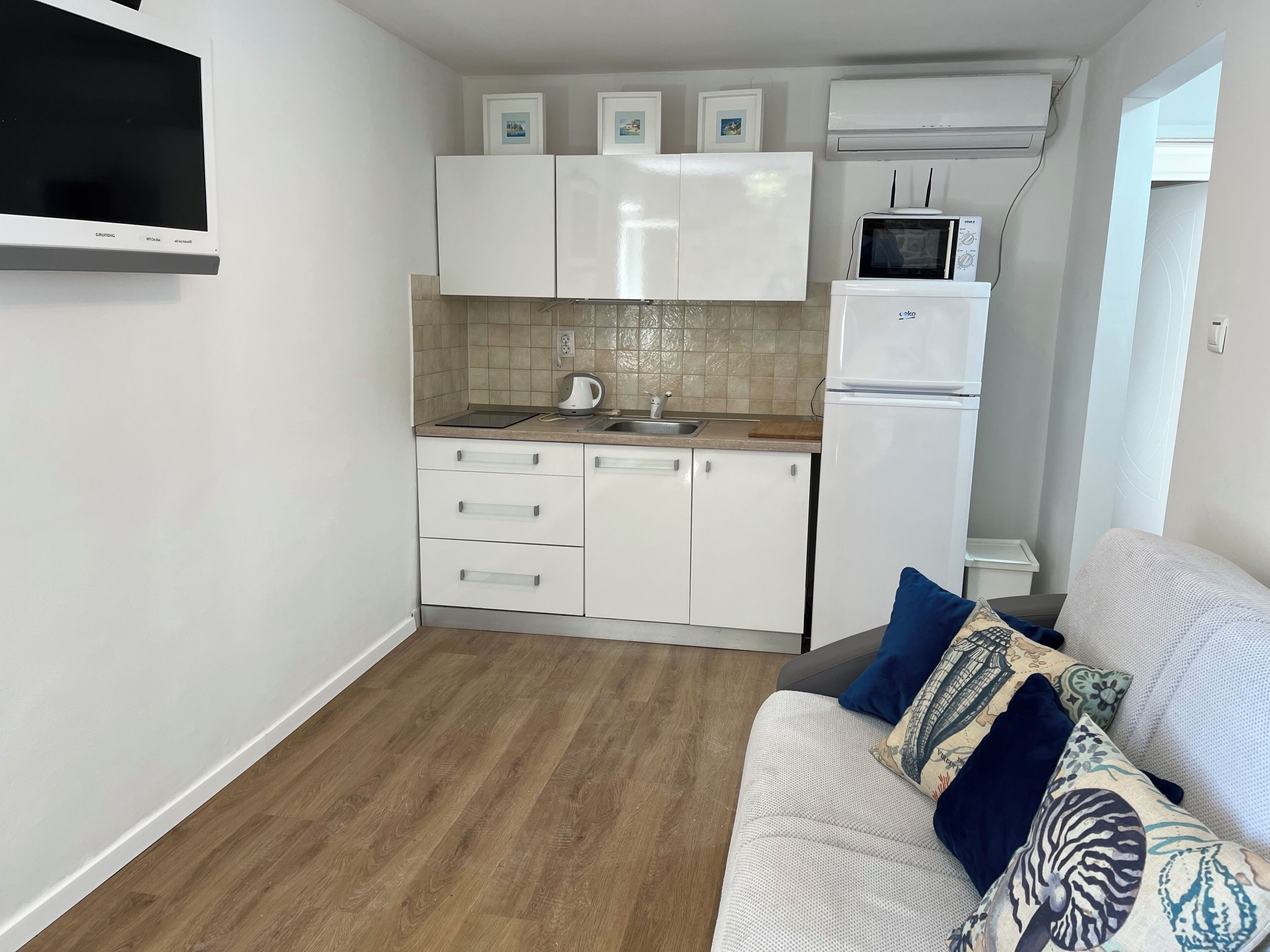 A compact kitchen with white cabinets, a built-in microwave, and a refrigerator.